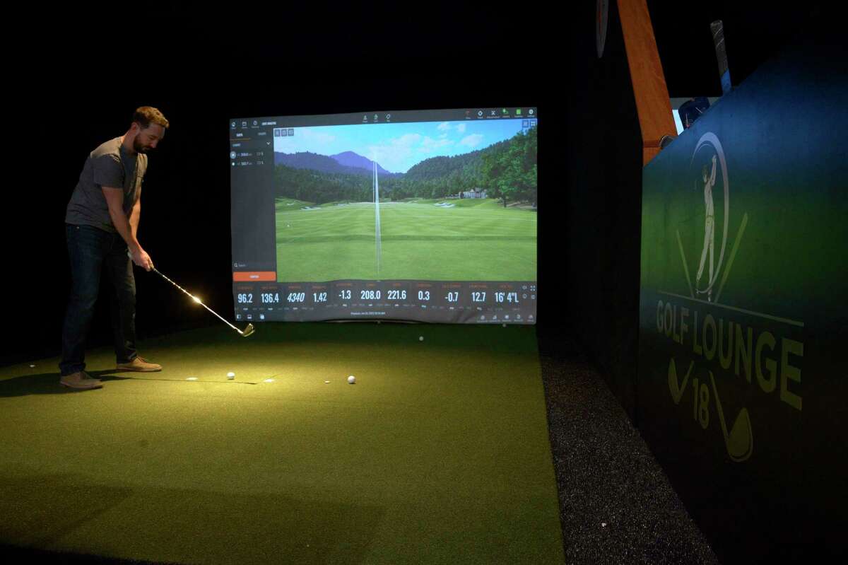 Bill Thode, of Ridgefield, sets up a shot during a simulation at Golf Lounge 18, a mix of a golf simulator, restaurant and bar, which has opened in the Danbury Fair mall in Danbury, Conn. Wednesday, January 26, 2022.