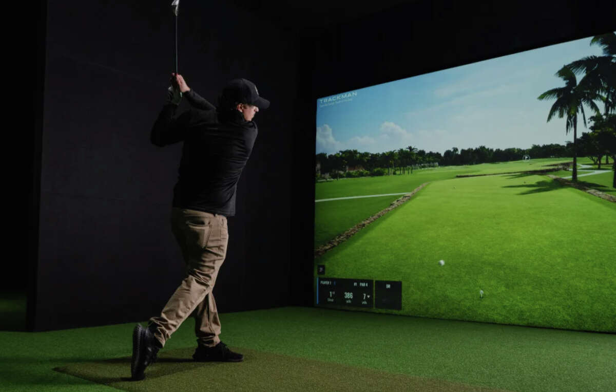 A golfer swings on one of Back 9 Social's virtual golf bays. 