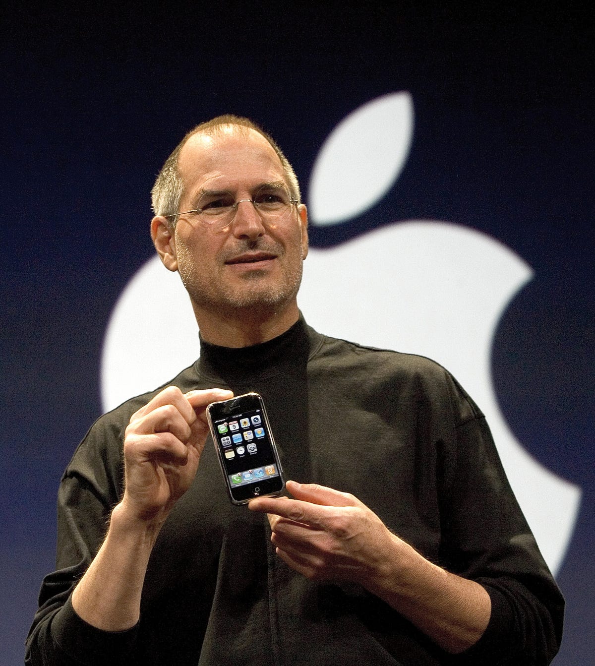 Steve Jobs in 2007, introducing the first iPhone, which he's holding in his hands