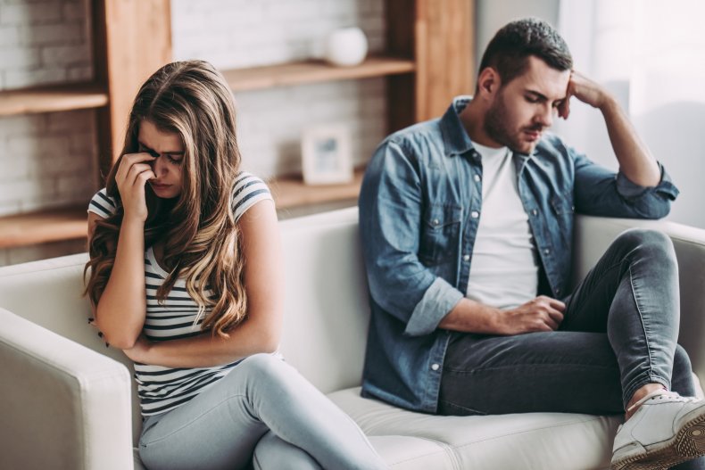 A couple looking upset on a sofa.