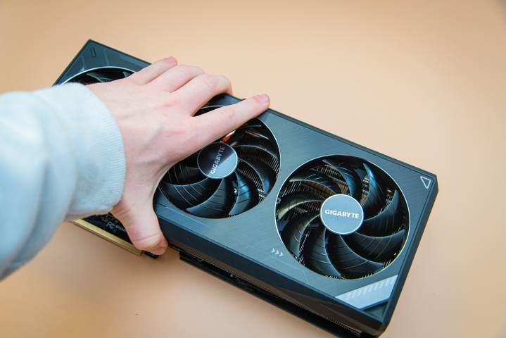 A hand grabbing the RTX 3090 Ti graphics card.