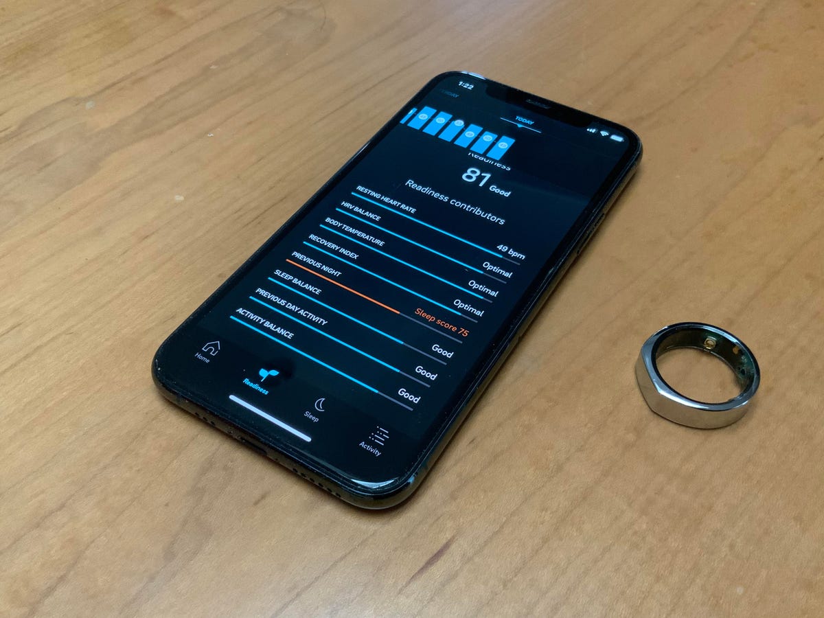 the Oura ring next to a phone showing its accompanying app