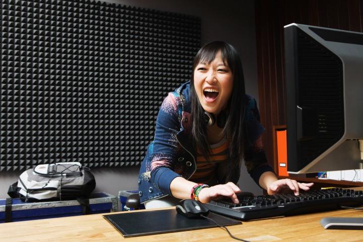 Woman shouting with joy while playing games on a PC.